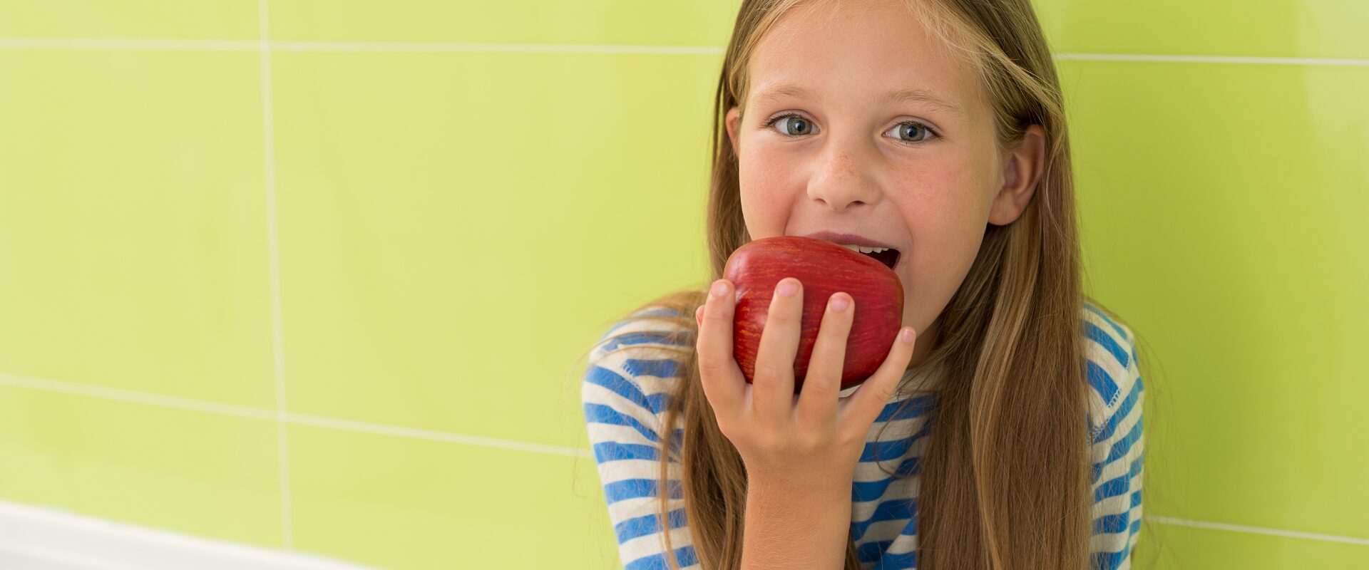 Middle school girl with long hair eating a red apple
