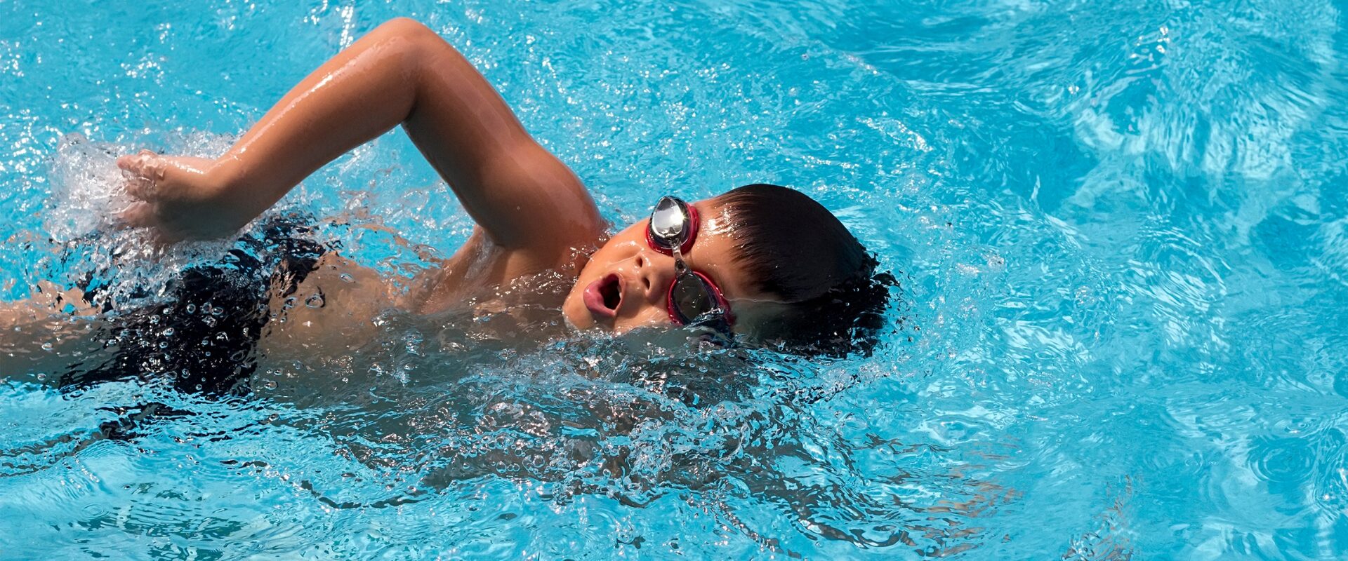 Boy wearing goggles swimming in pool