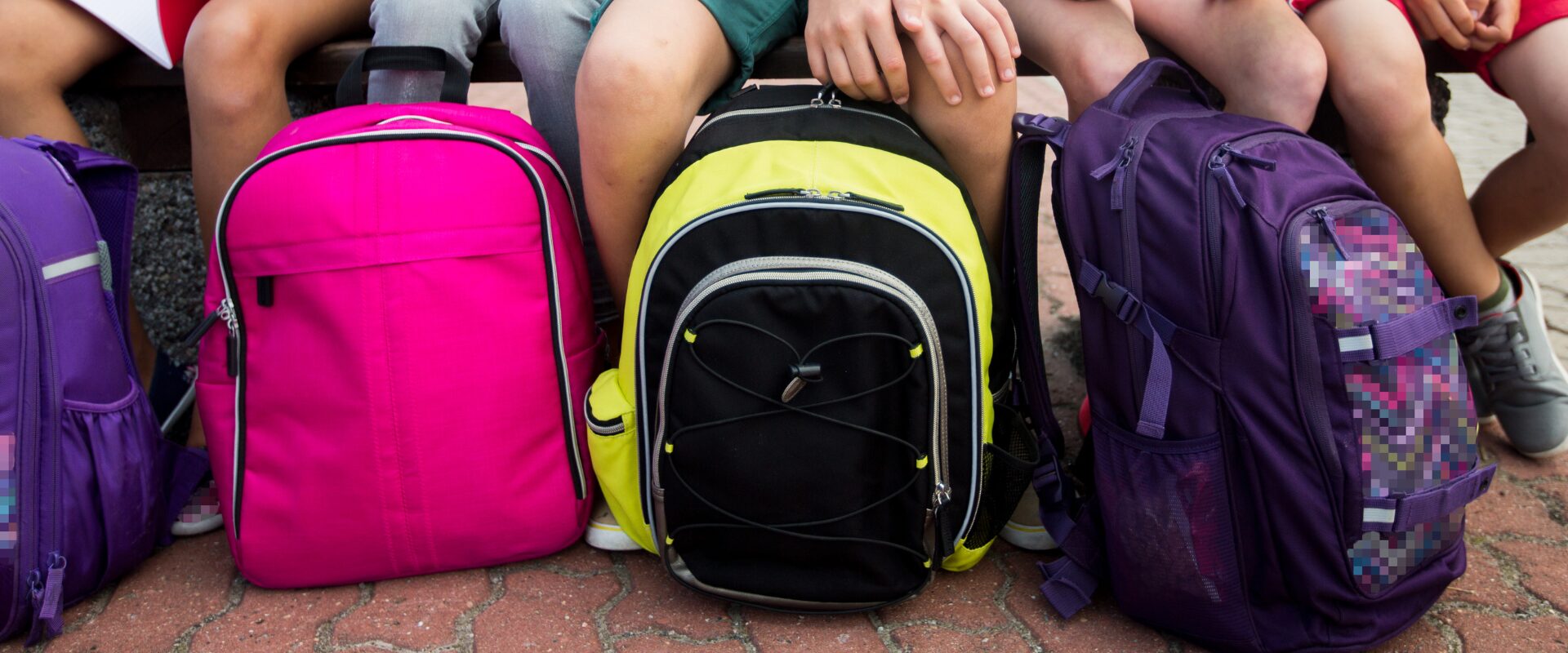 Backpacks sitting on floor in front of kids