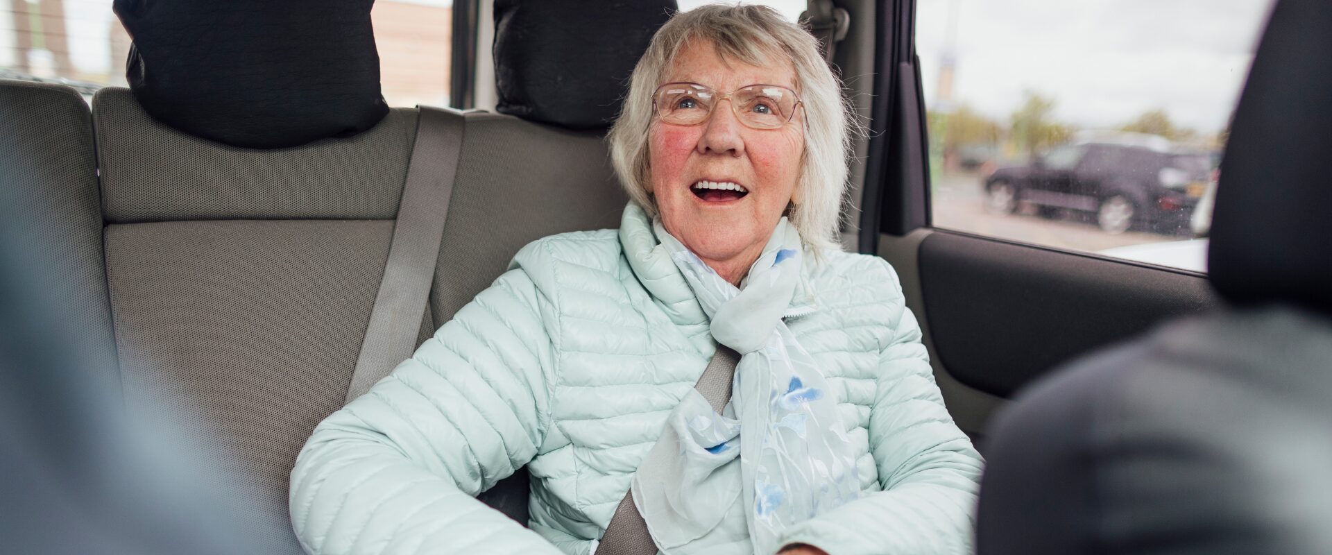 Smiling older woman in back seat of car