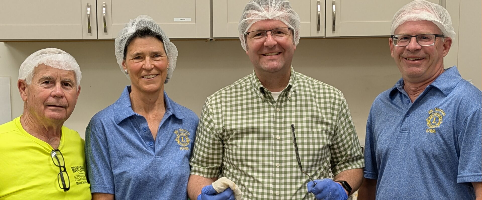 Volunteers wearing head coverings standing in kitchen