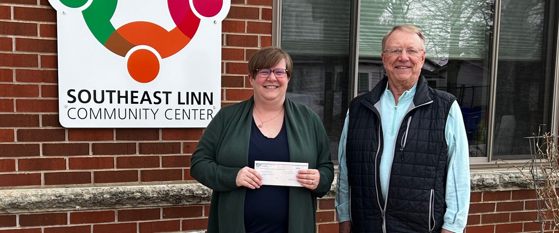 Donor Fred Burke and Southeast Linn Community Center Executive Director Nicole McAlexander posing with a check outside the SELCC building