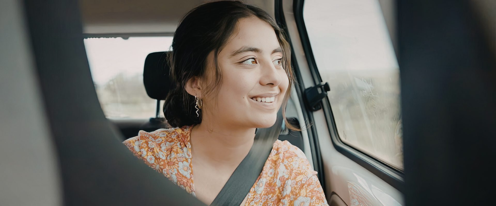 Young woman in passenger seat looking out car window