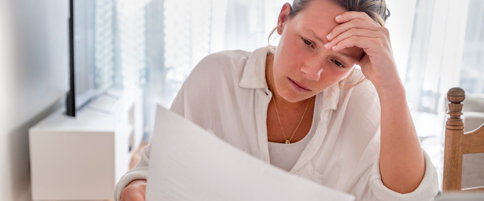 Dismayed young woman looking at bill